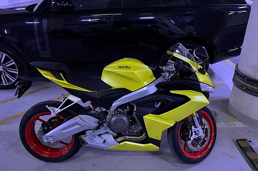 a yellow motorcycle parked next to a black car